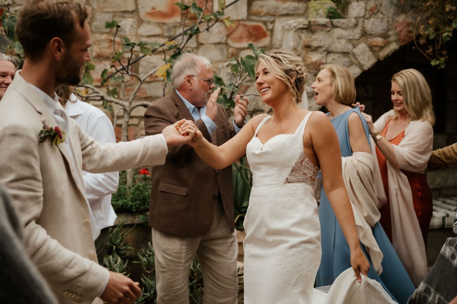 Wedding celebration in a rustic stone courtyard with dancing and joyful moments.