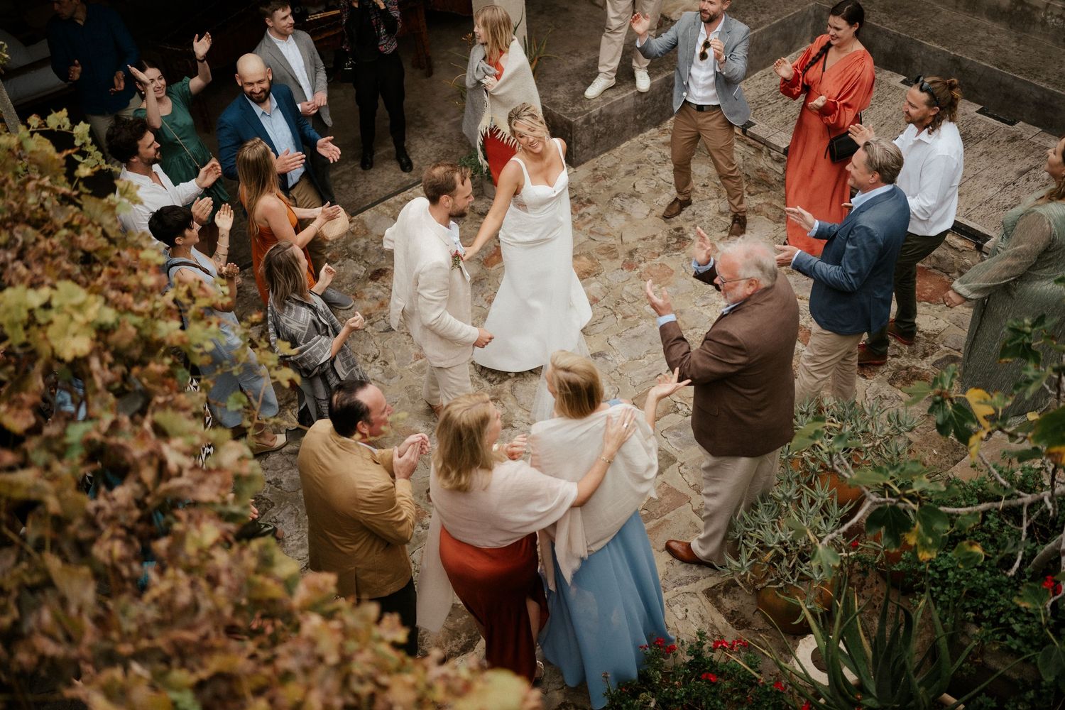 Bird's eye view of wedding celebration with guests gathered in stone courtyard.