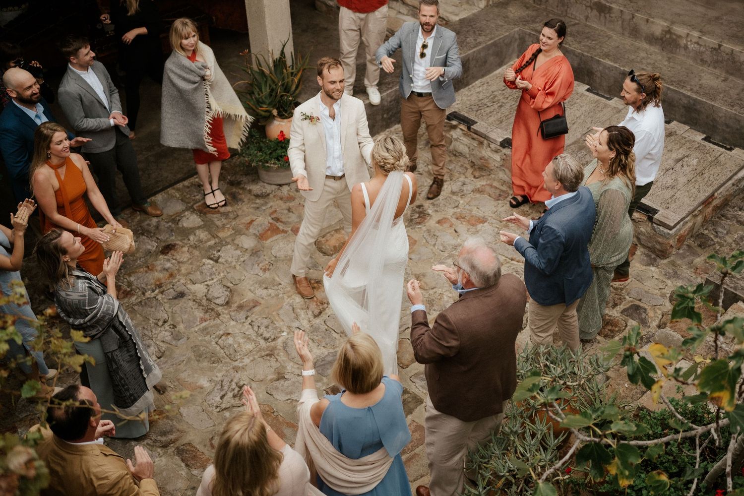 Wedding celebration in a rustic courtyard with guests gathered around watching the festivities.
