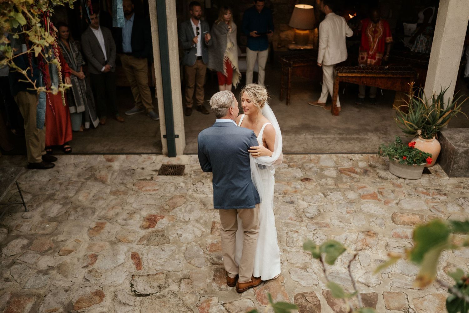 Intimate moment shared during wedding celebration on stone patio courtyard.