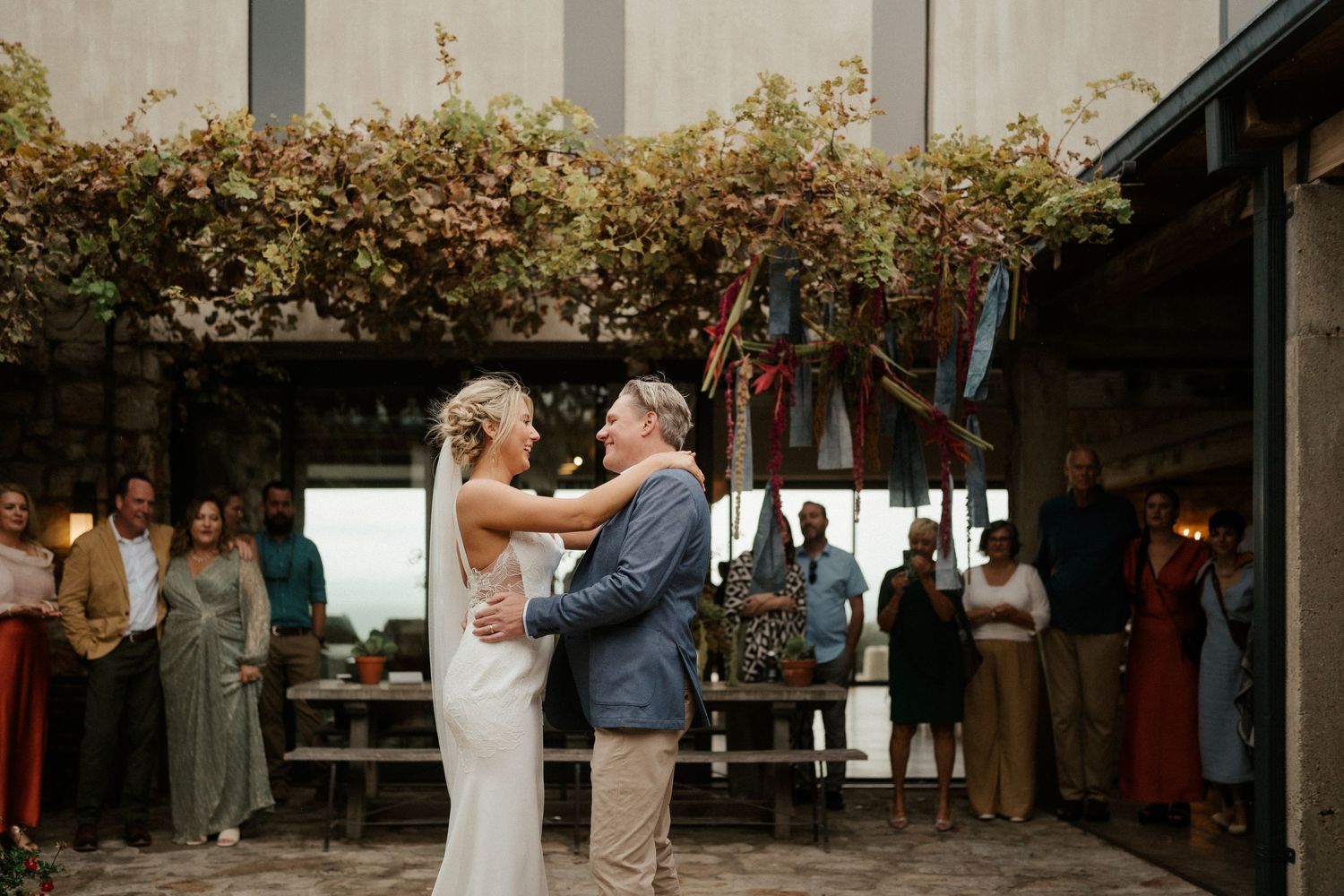 A couple exchanges vows during an intimate outdoor ceremony with guests watching nearby.