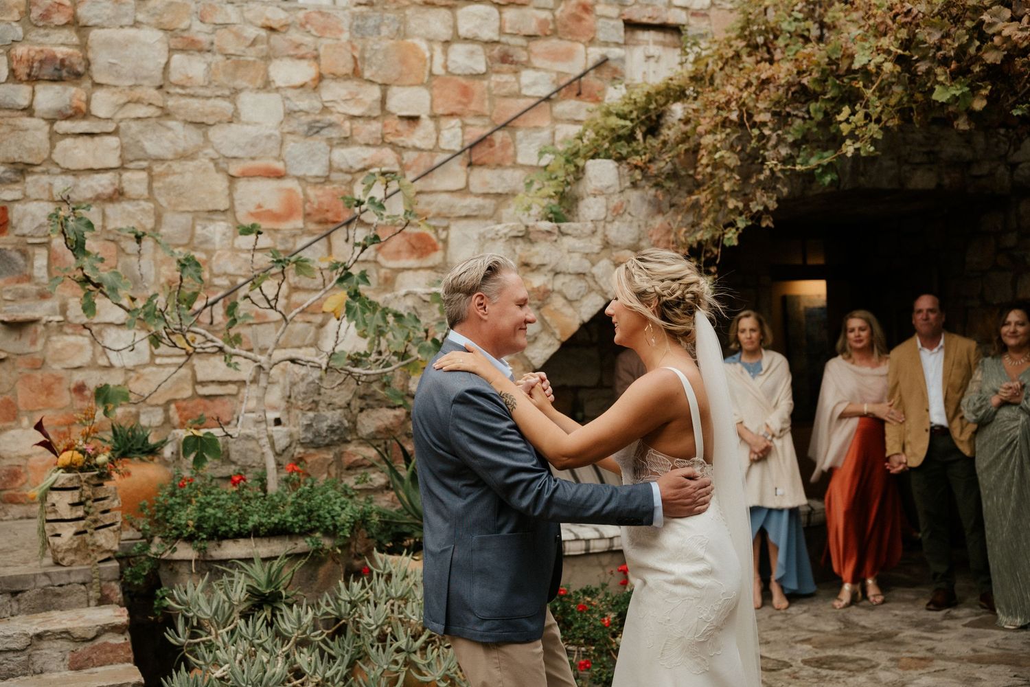 A joyful wedding celebration moment in front of a rustic stone wall adorned with climbing vines.