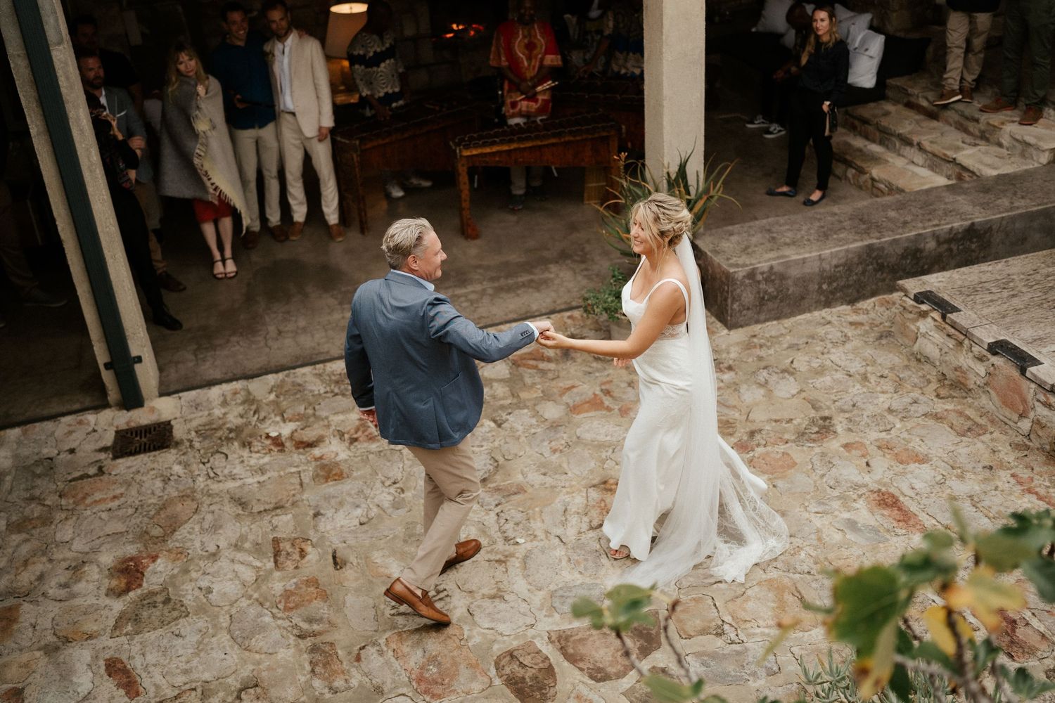 Couple dances together on a stone patio during their wedding celebration.