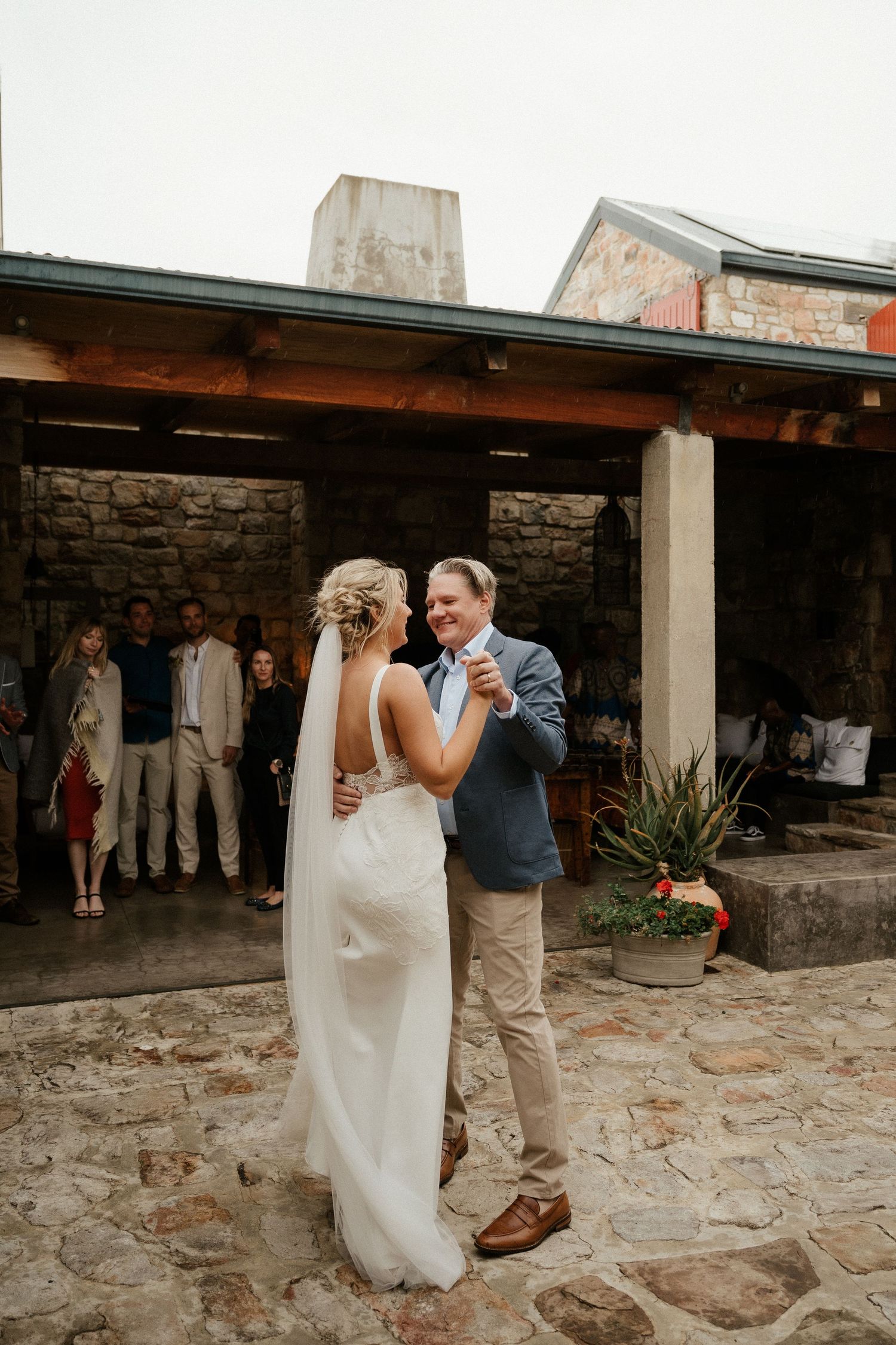 Couple shares their first dance on a rustic stone patio during an intimate outdoor wedding celebration.