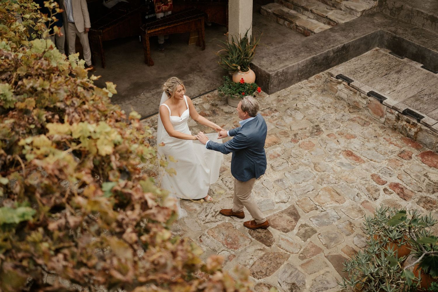 An intimate outdoor wedding ceremony moment captured from above on a stone patio.