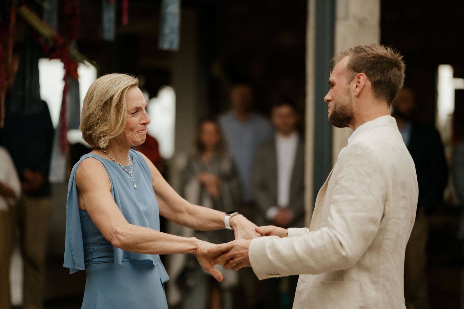Wedding guests sharing a dance moment in casual attire at an indoor venue.
