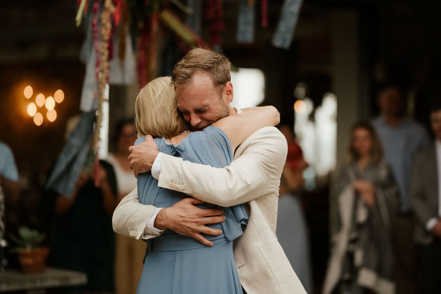 An emotional embrace during a wedding reception with warm lighting in the background.