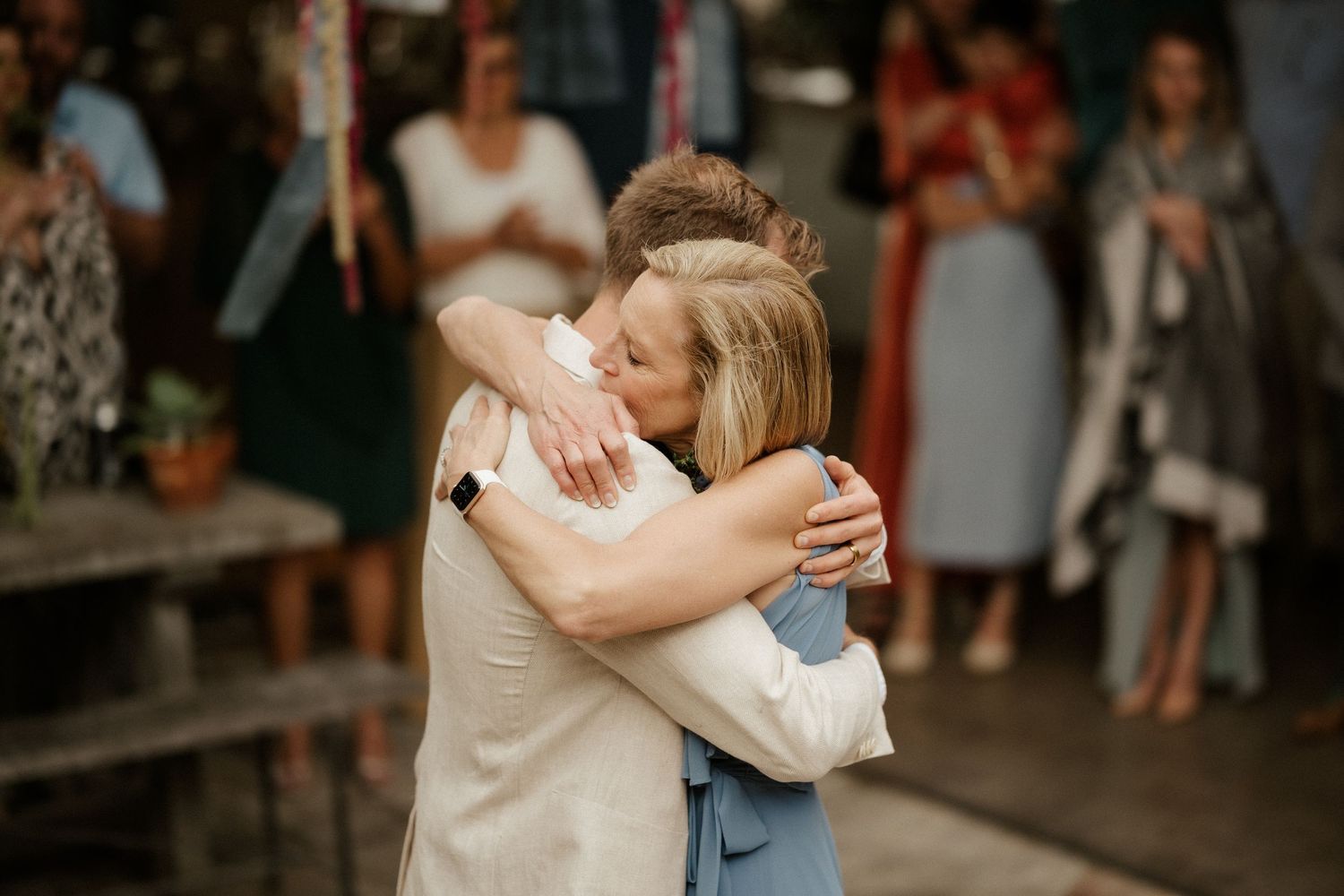 An emotional embrace shared during a wedding celebration in a dimly lit indoor venue.