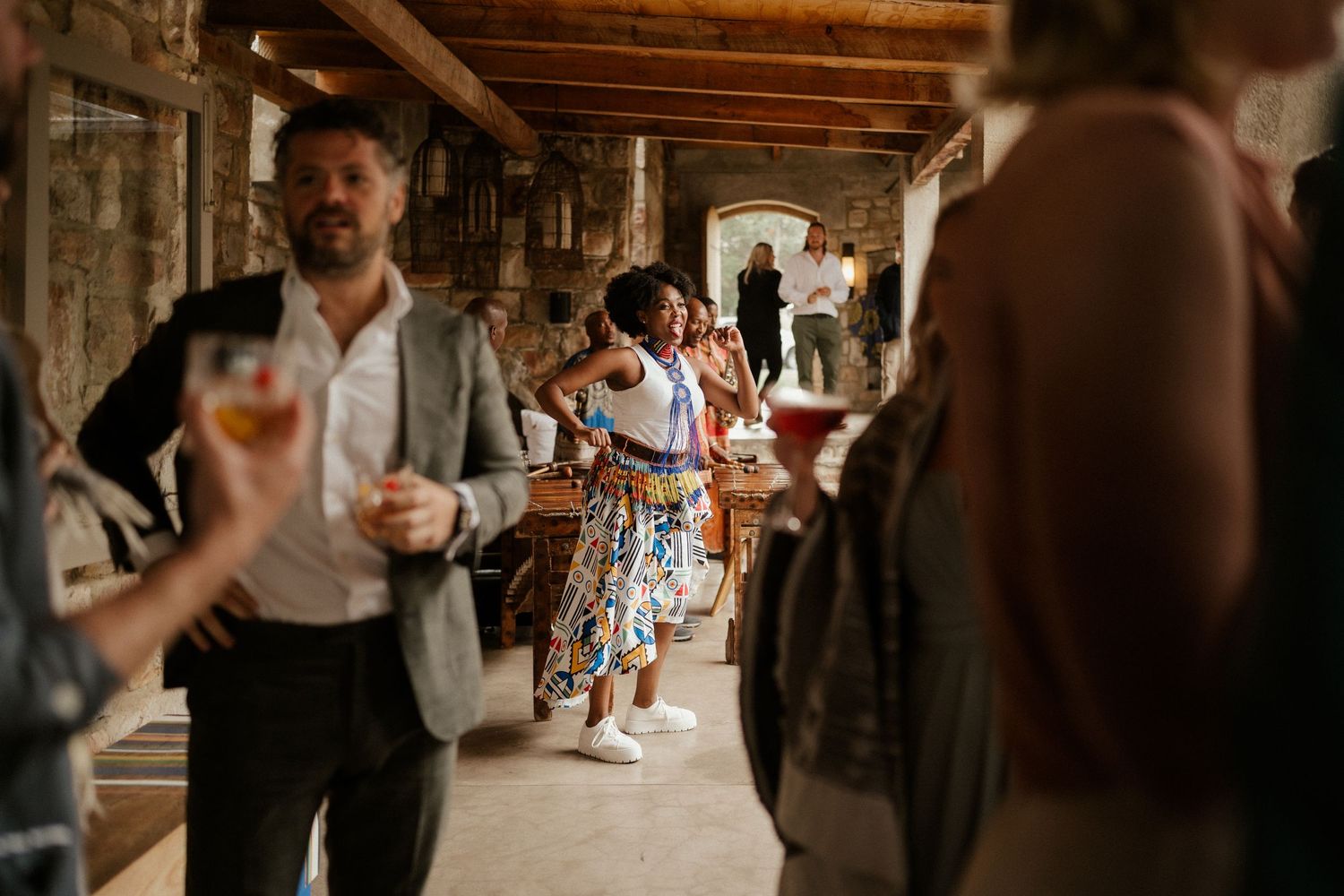 People dancing and celebrating in a rustic stone hallway during a festive event.