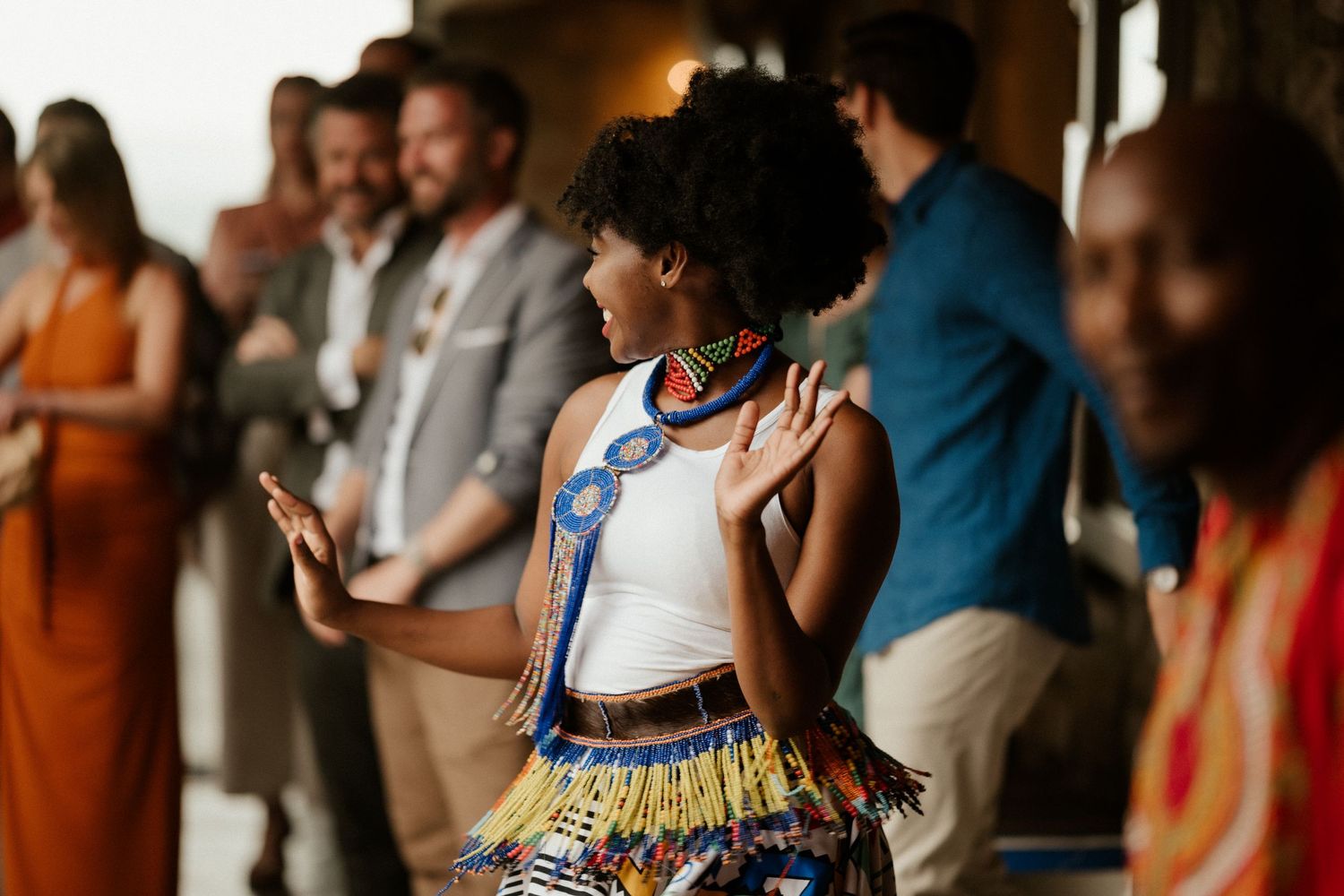 Wedding guest in a vibrant patterned dress dances energetically at the reception celebration.