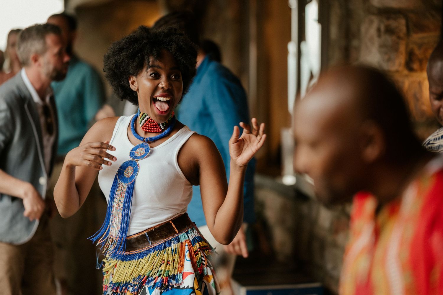 A woman in traditional African dress dances joyfully at a celebration event.