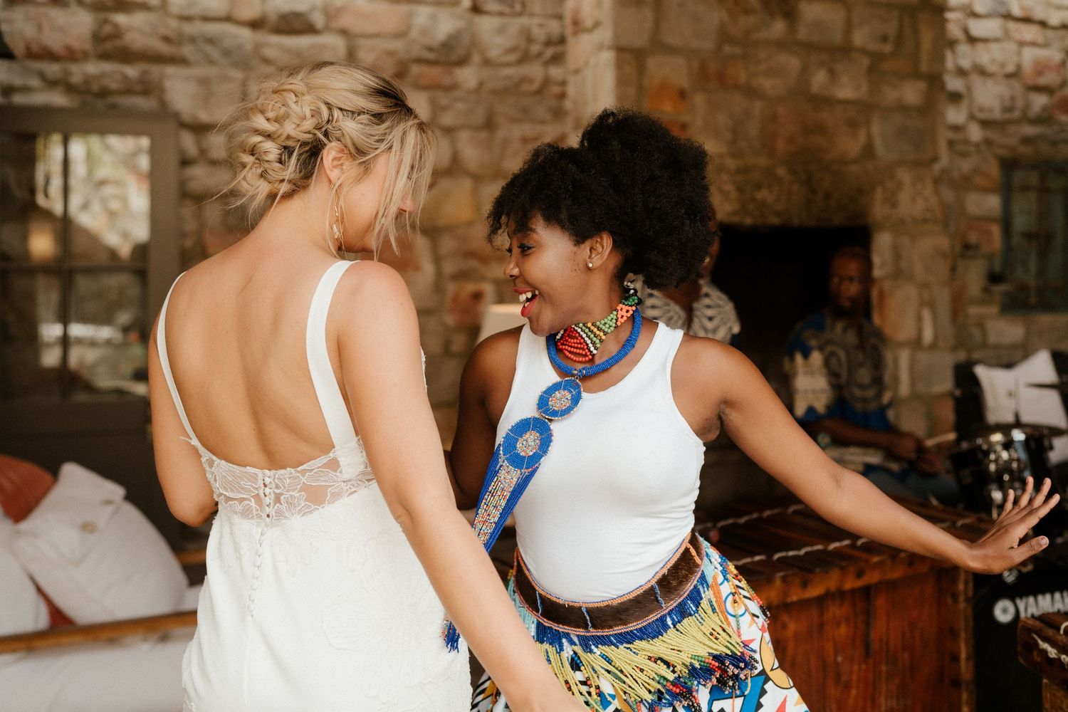 Two people dancing and celebrating at a wedding reception in a rustic stone venue.