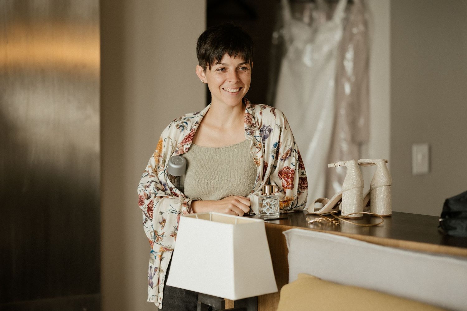 A person in a floral print jacket smiles while holding a shopping bag in an indoor setting.