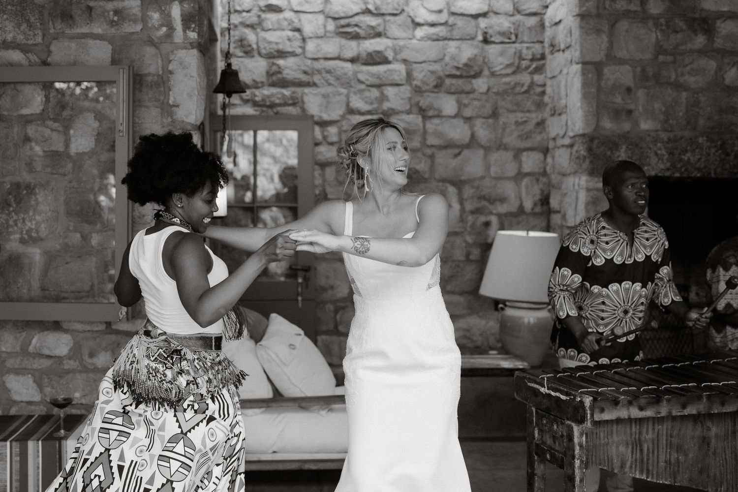 Wedding celebration with dancing in a rustic stone venue with people enjoying the festivities.
