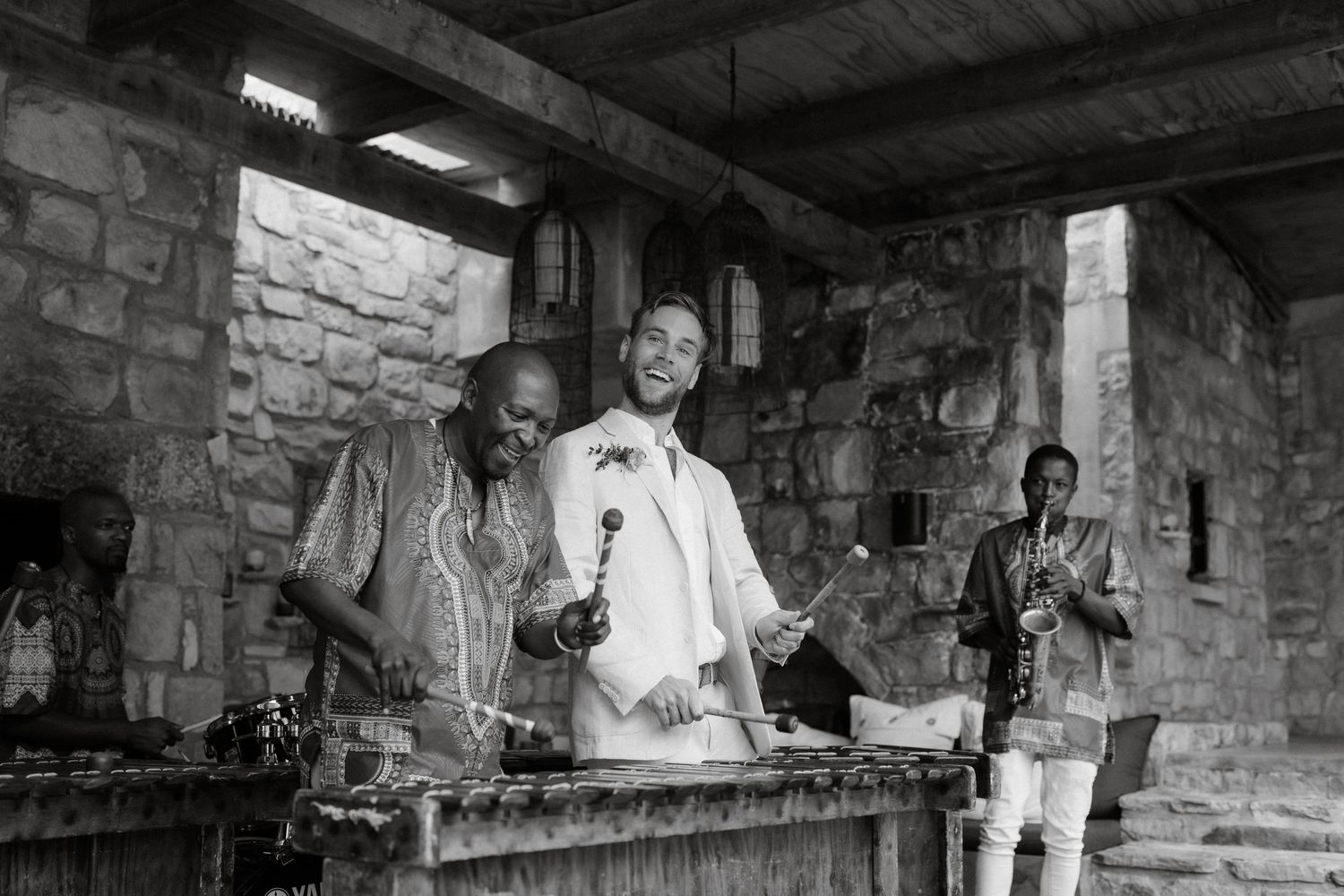 Black and white photo of performers playing marimba instruments in a stone-walled venue.