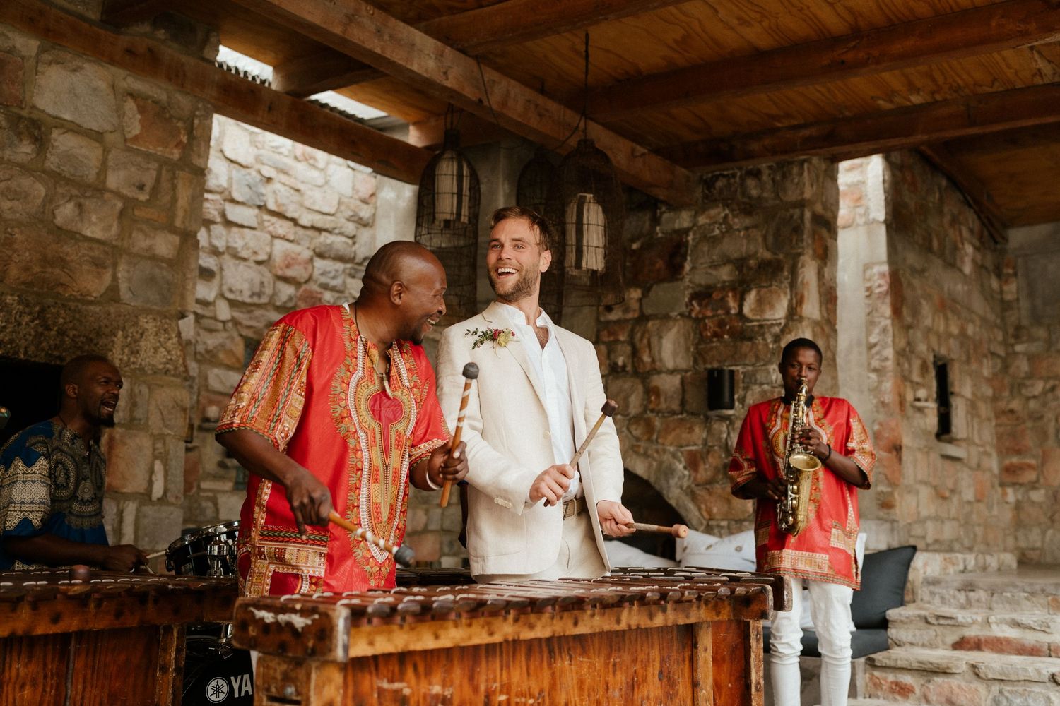 Musicians perform on traditional wooden instruments in a rustic stone building interior.