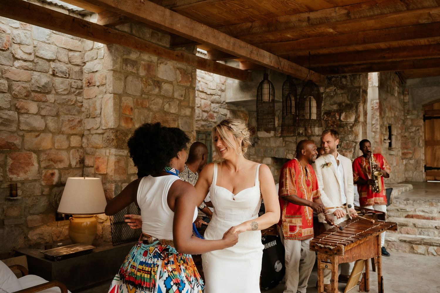 A wedding celebration takes place in a rustic stone basement with exposed beams and warm lighting.