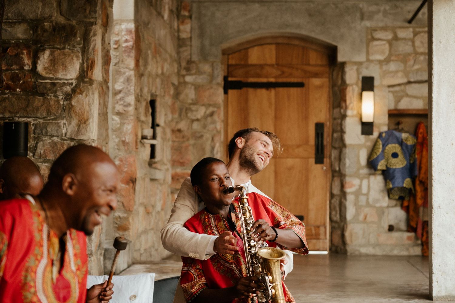 Musicians performing with a saxophone at a wedding celebration in a stone-walled venue.