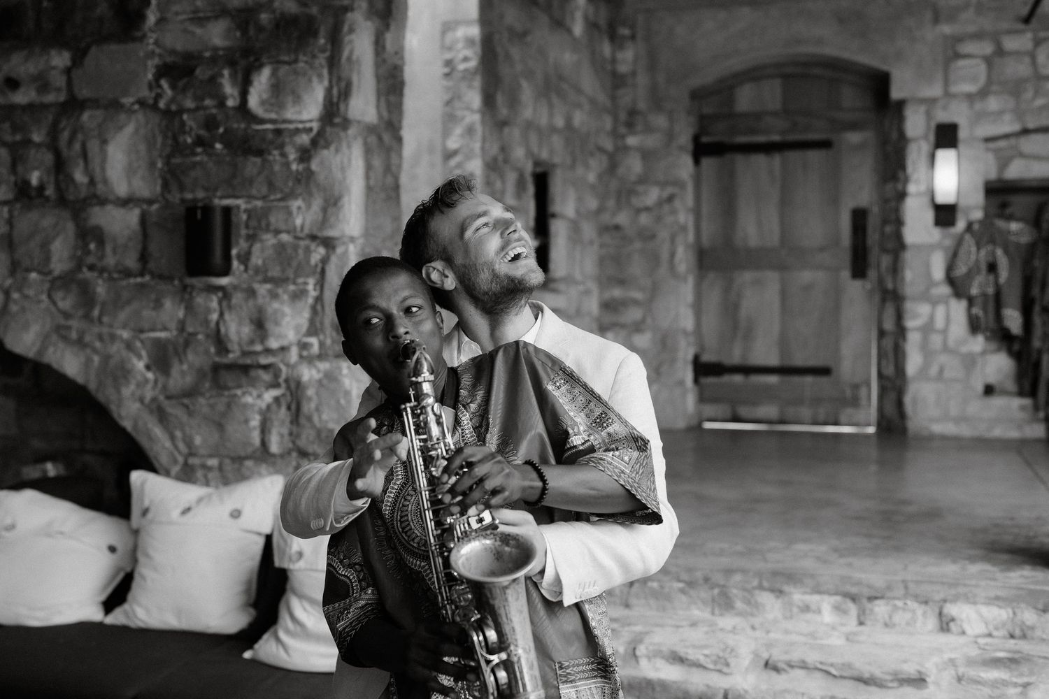 A joyful celebratory moment captured in black and white at a rustic stone venue.