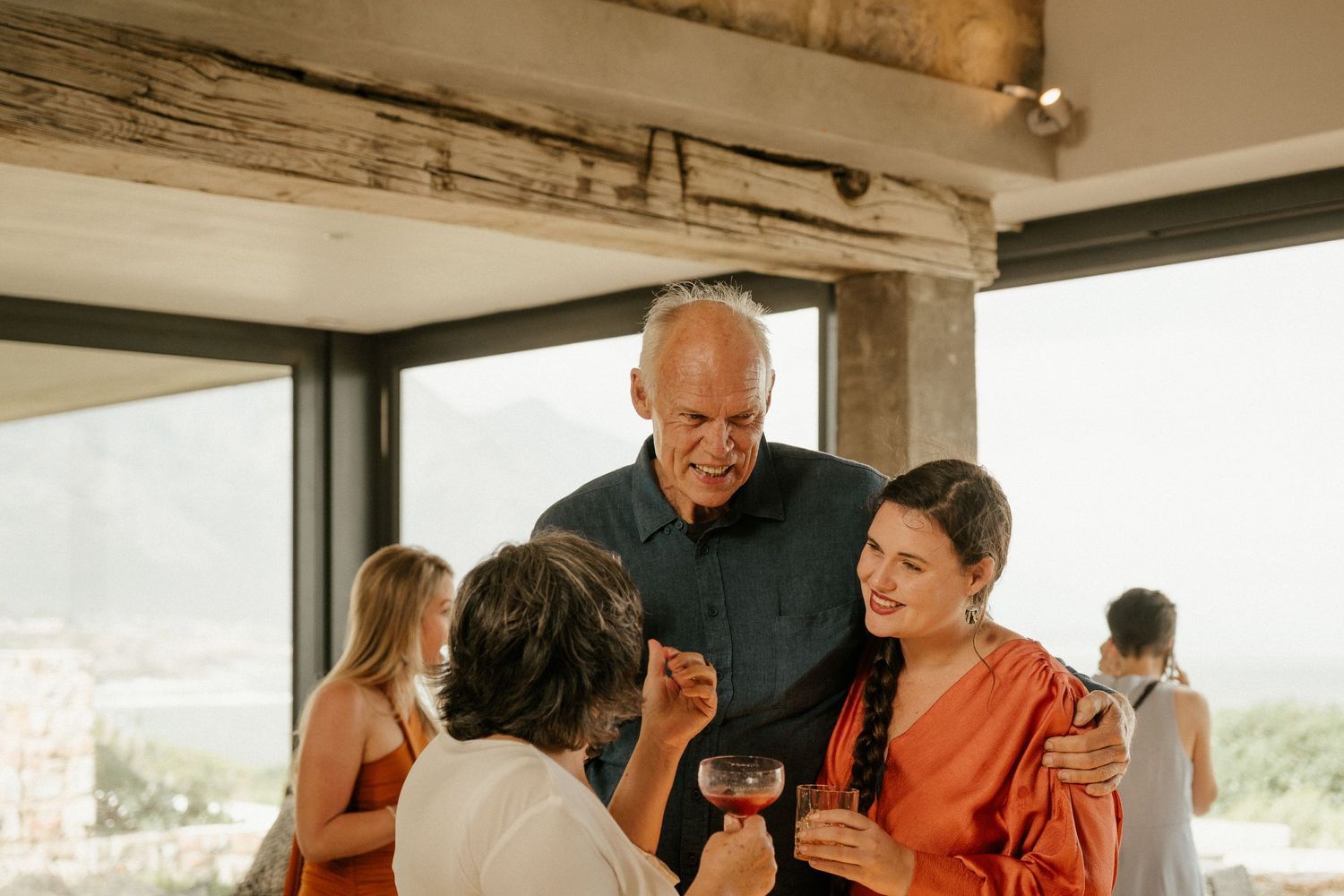 Group enjoying conversation during a social gathering in a modern room with wooden beams.
