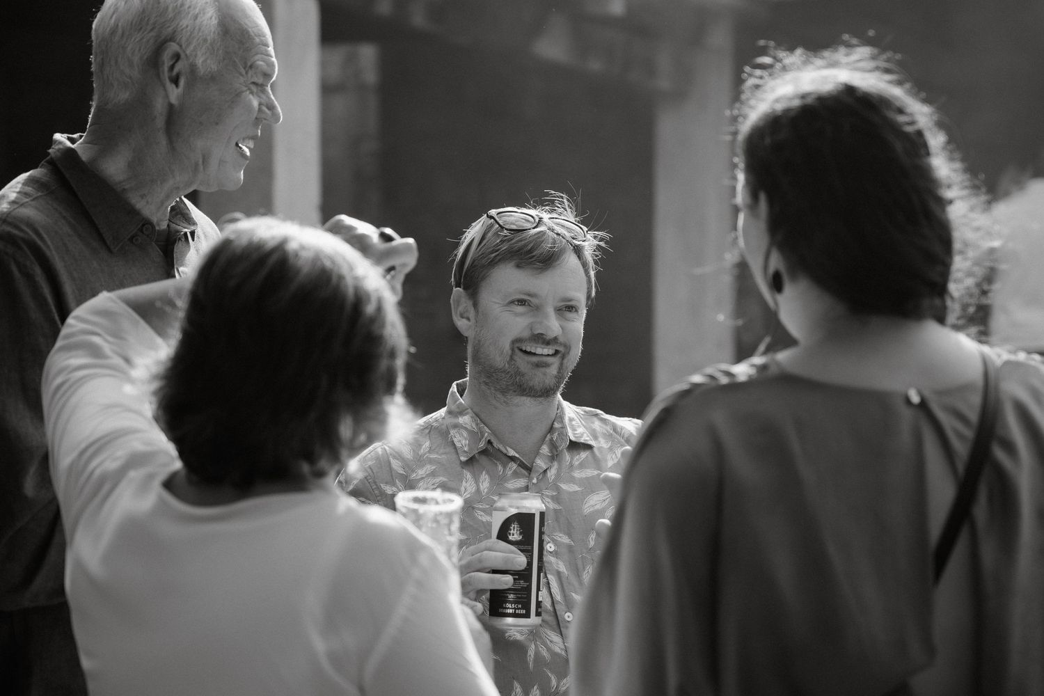 A casual gathering of people sharing drinks and laughter in black and white.