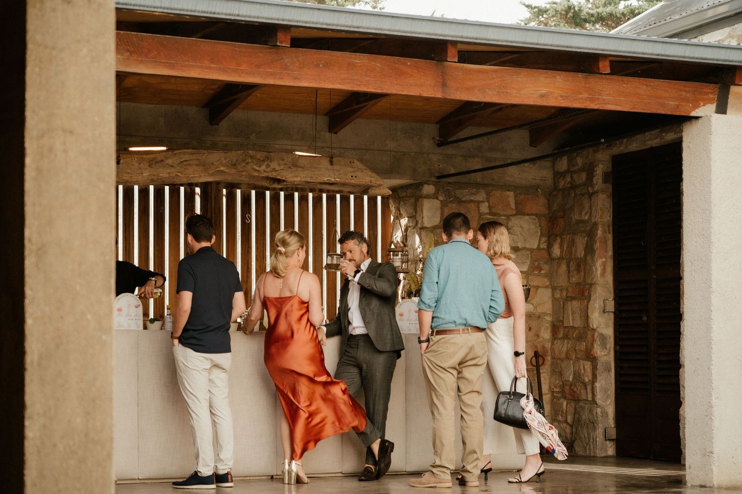 Wedding guests walking through a covered stone passageway in casual attire.