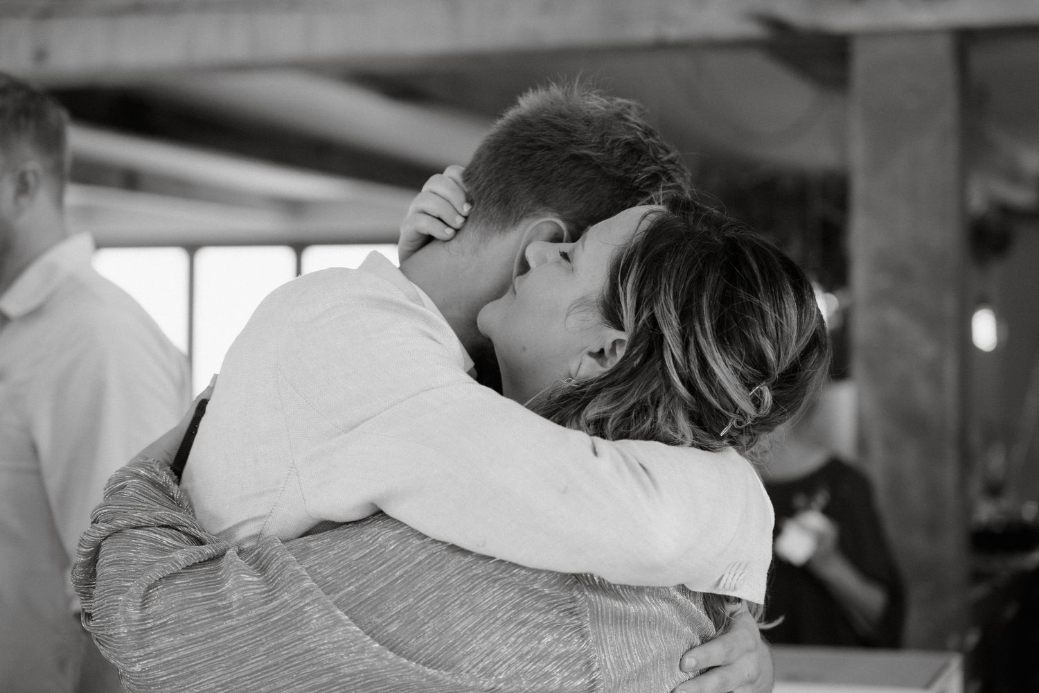 An intimate black and white moment of a couple embracing at their wedding celebration.