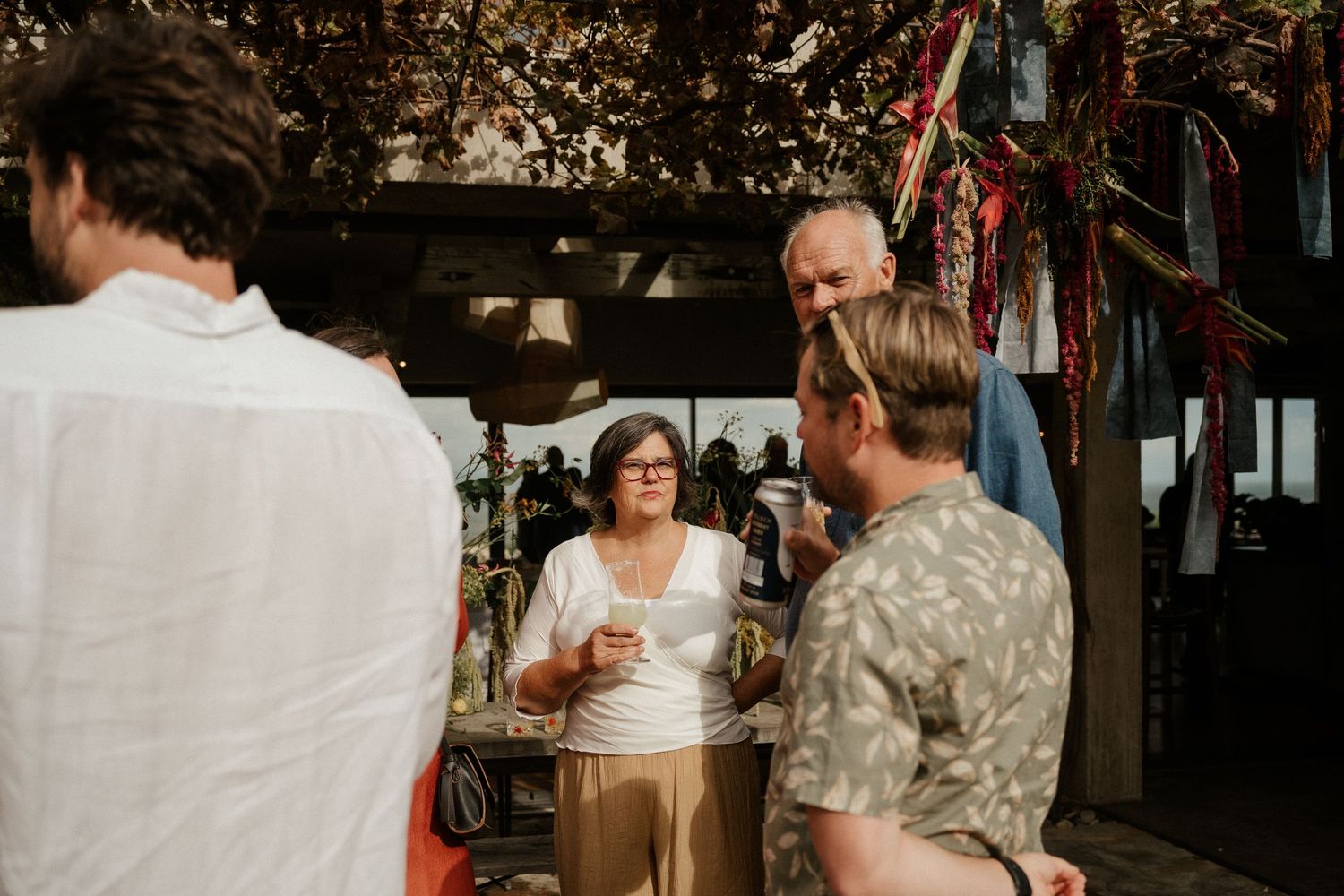 A casual outdoor wedding gathering with guests mingling under decorative hanging elements.