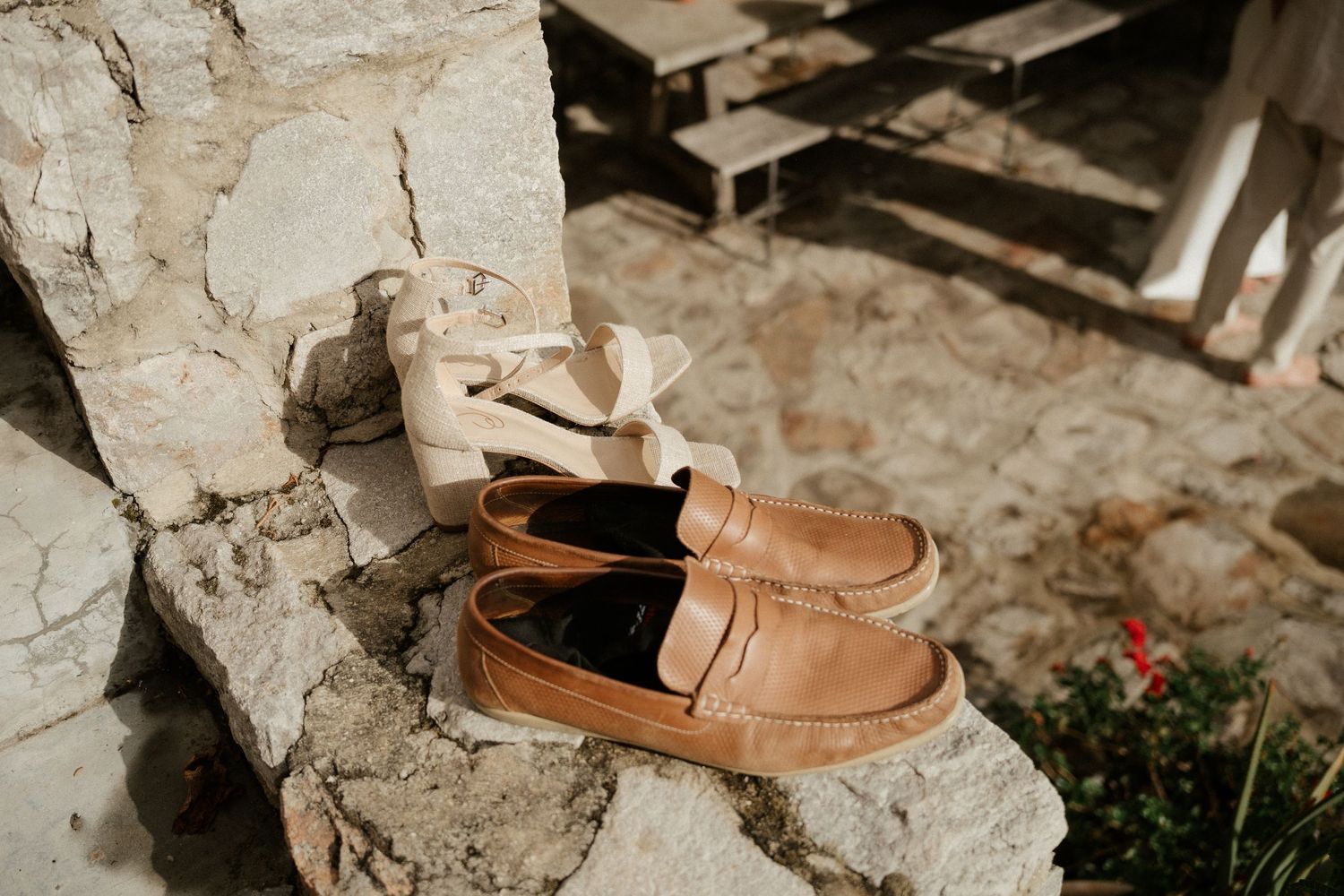 A pair of tan leather loafers sitting on a rustic stone ledge in natural lighting.