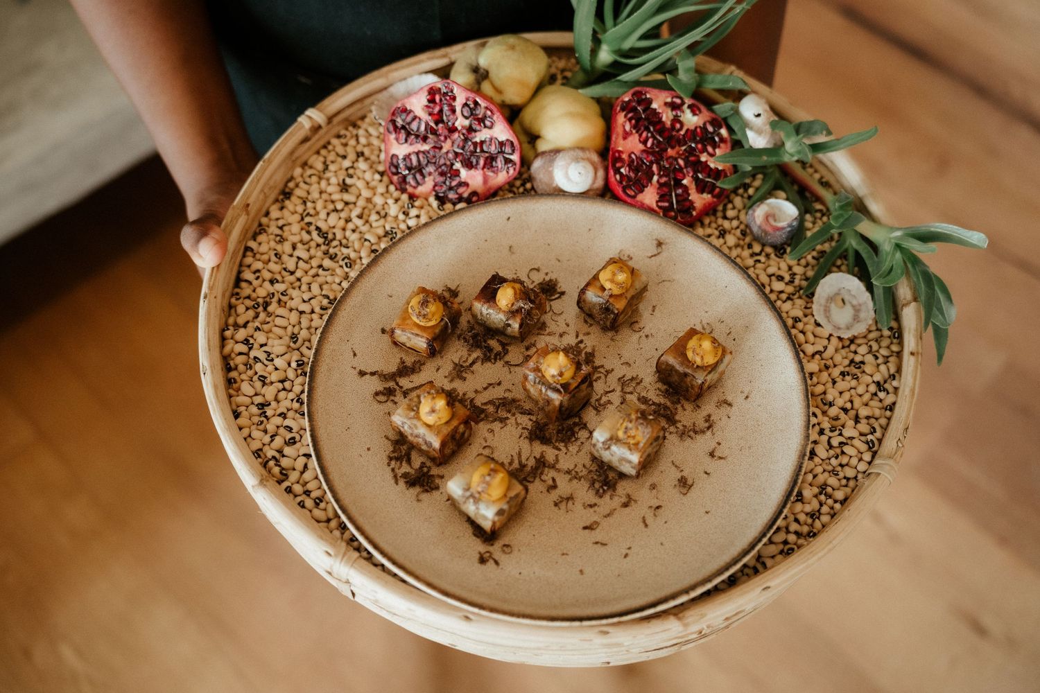 An elegant plate of roasted vegetables garnished with pomegranate and herbs on a textured ceramic plate.