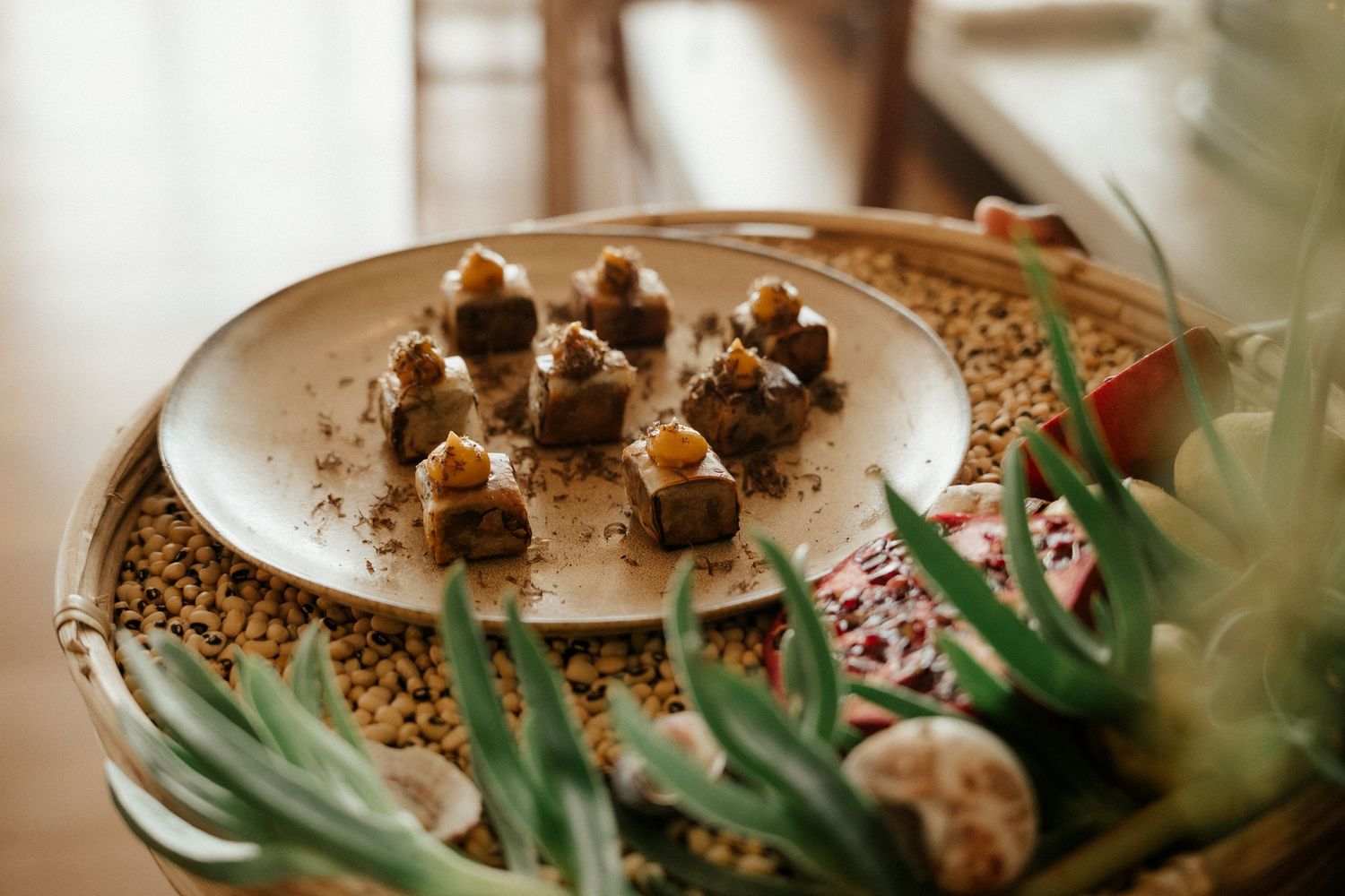Small chocolate desserts are elegantly plated on white dishware with decorative greenery.