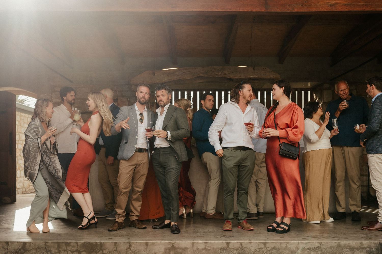 A group of wedding guests line up against a wall at an evening reception, creating a festive party atmosphere.