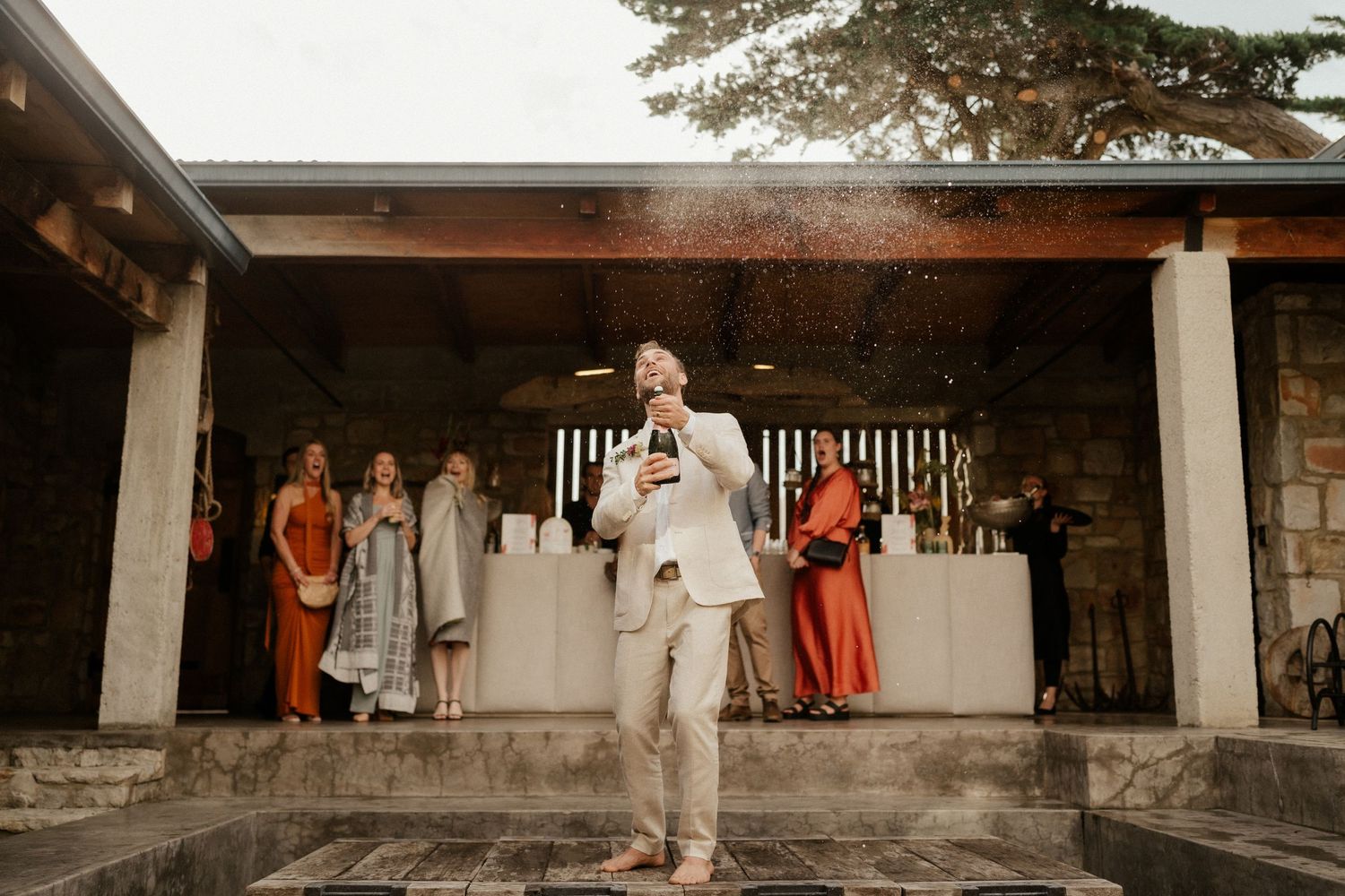 Wedding celebration at an outdoor stone venue with guests in colorful attire.