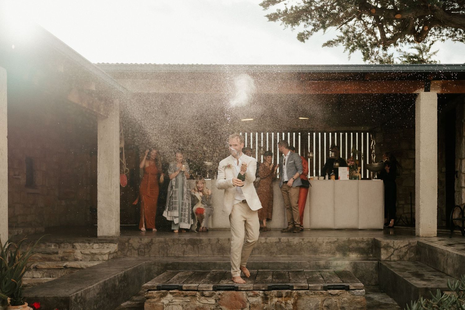 Sun-drenched gathering with guests mingling on a covered patio.