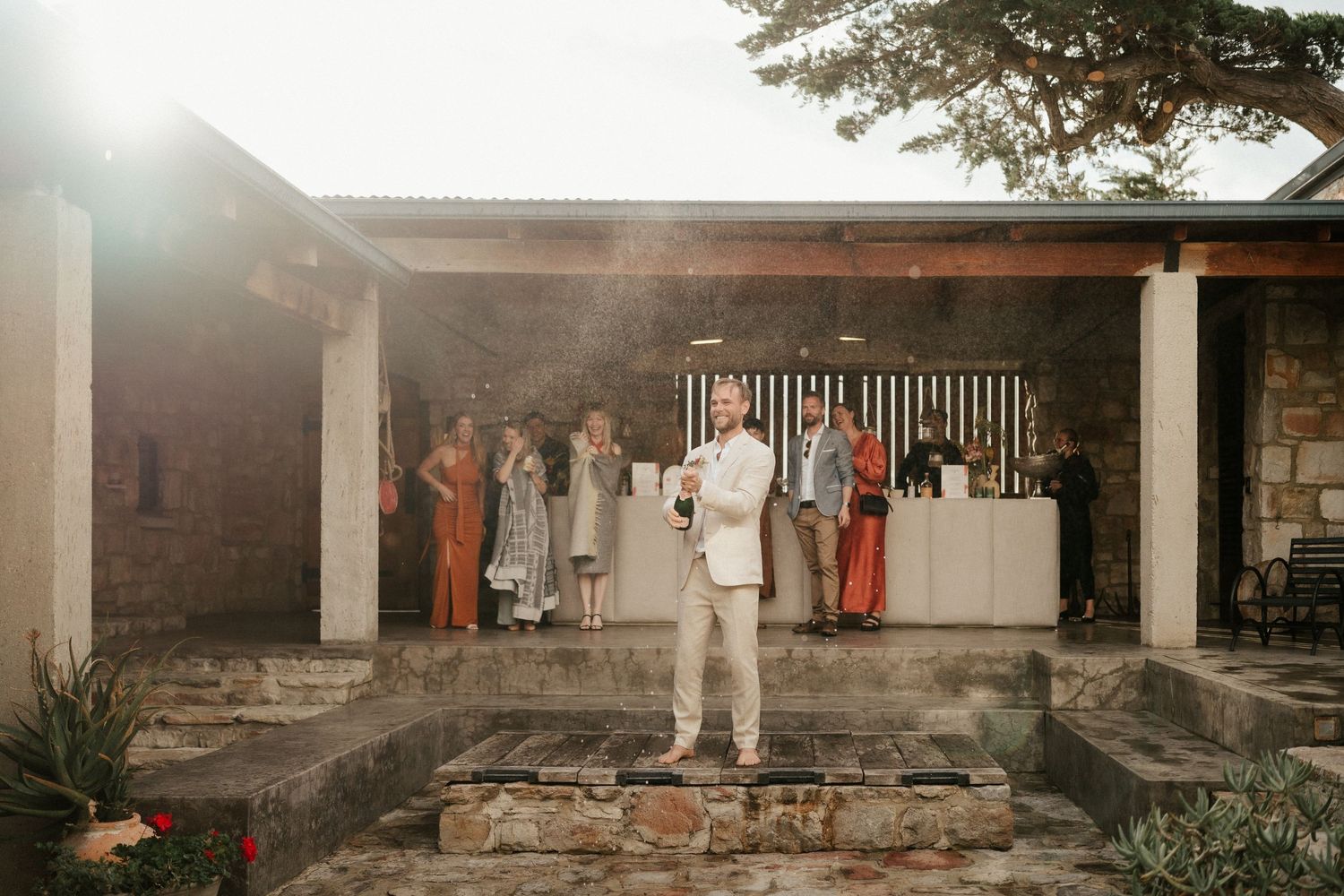Wedding reception at rustic stone venue with guests mingling at sunset.