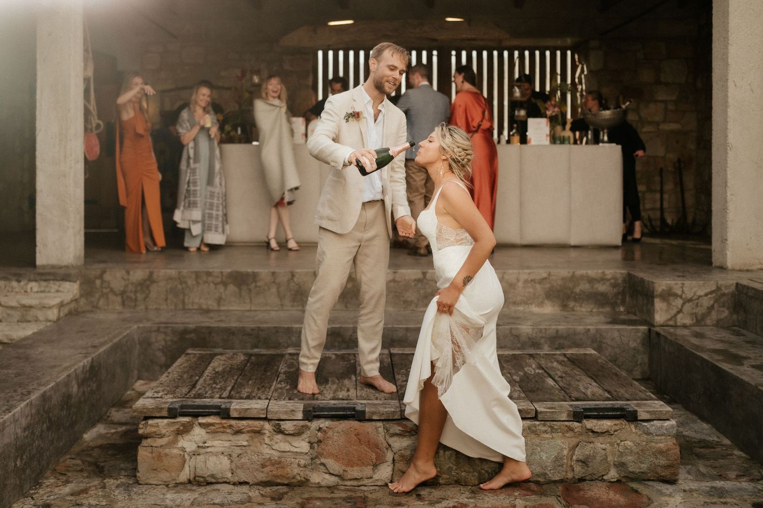 A couple in matching light outfits dance together at their reception.