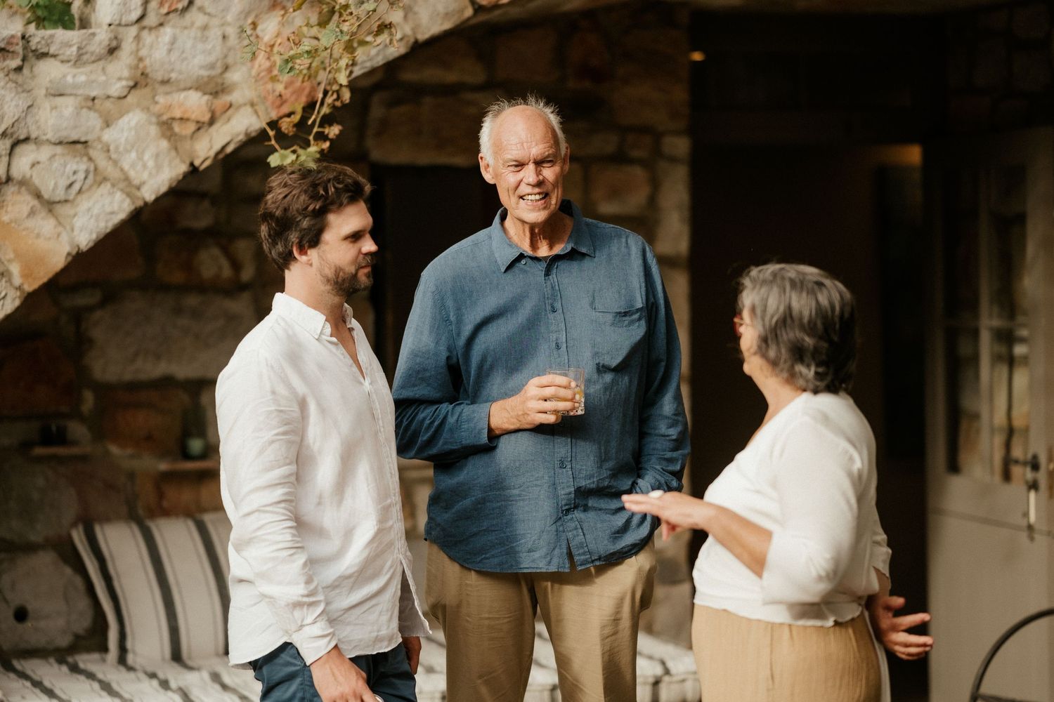 Three people having an animated conversation on a stone patio.