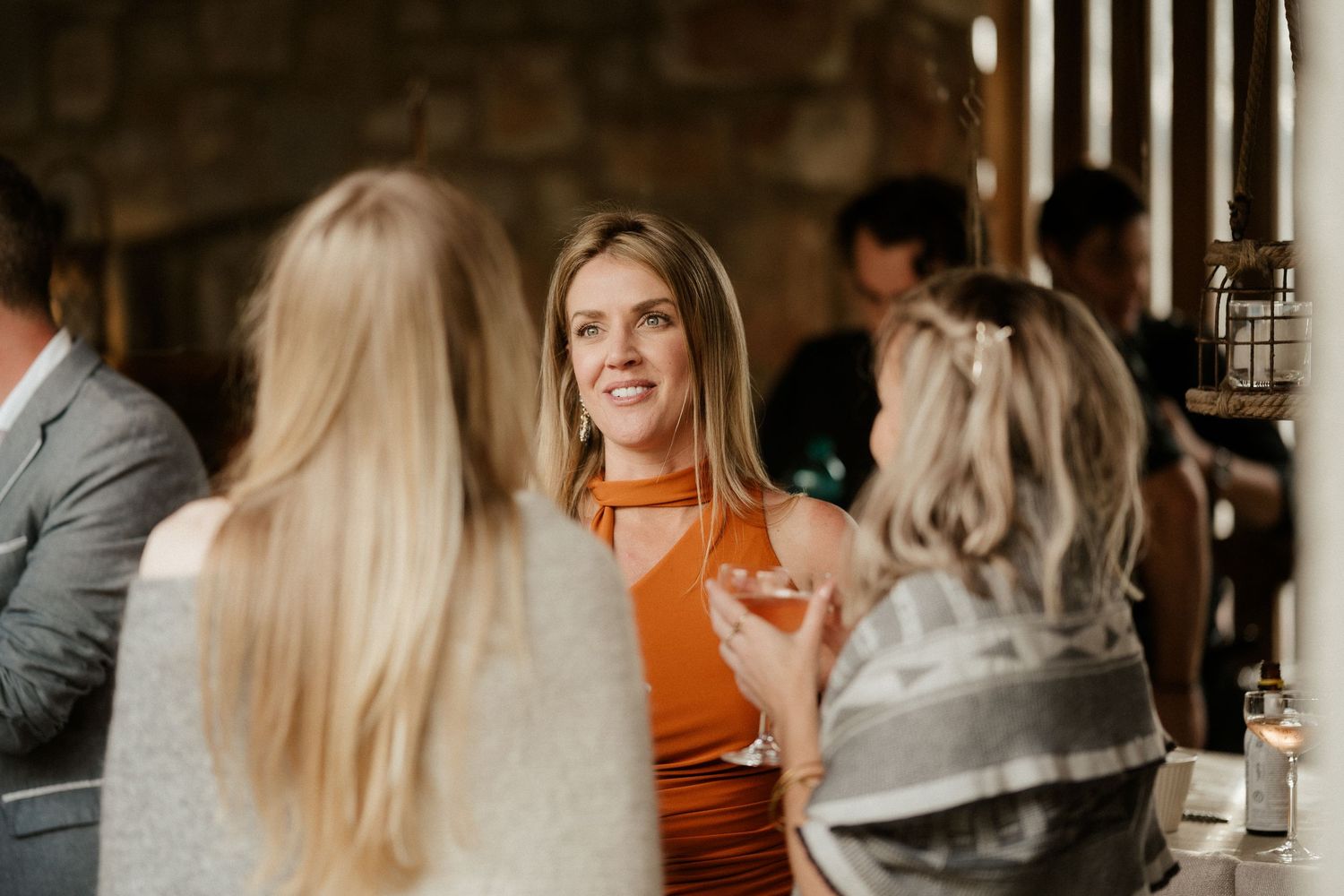 Social gathering with guests enjoying drinks and conversation at an indoor venue.