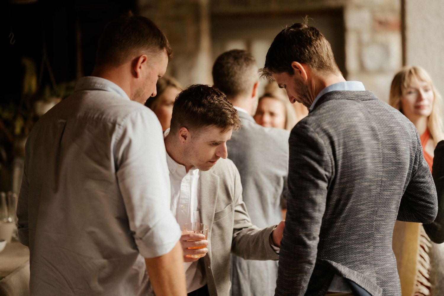 A group of guests chatting and socializing at an indoor wedding gathering.