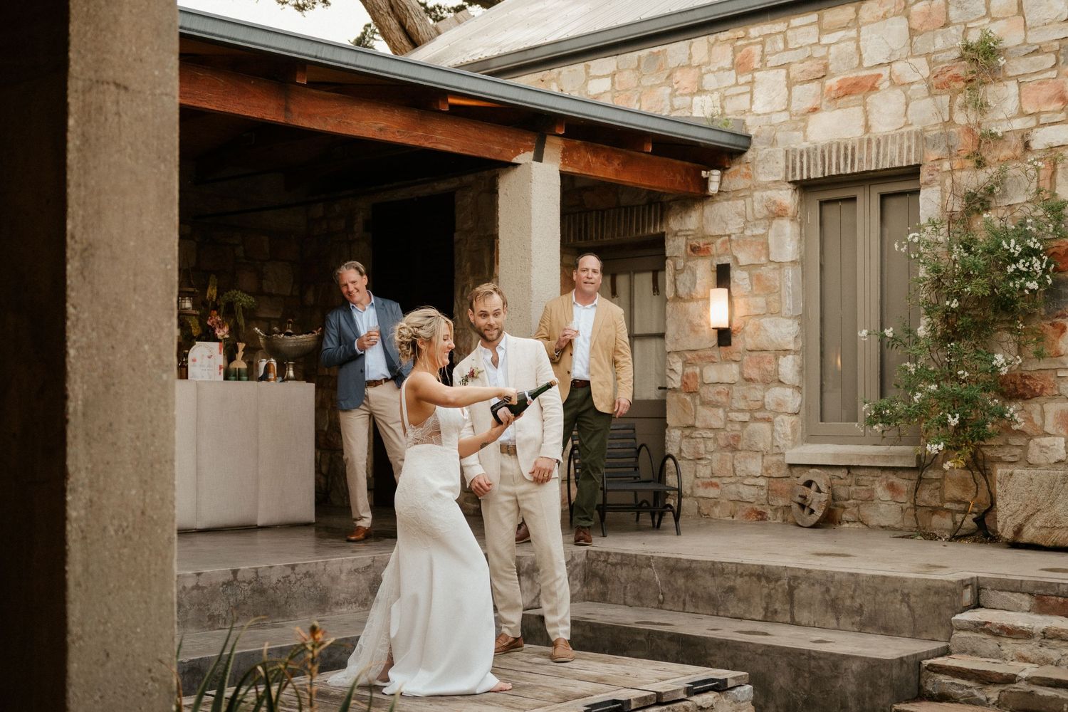 Wedding celebration at a rustic stone venue with guests mingling on a patio.