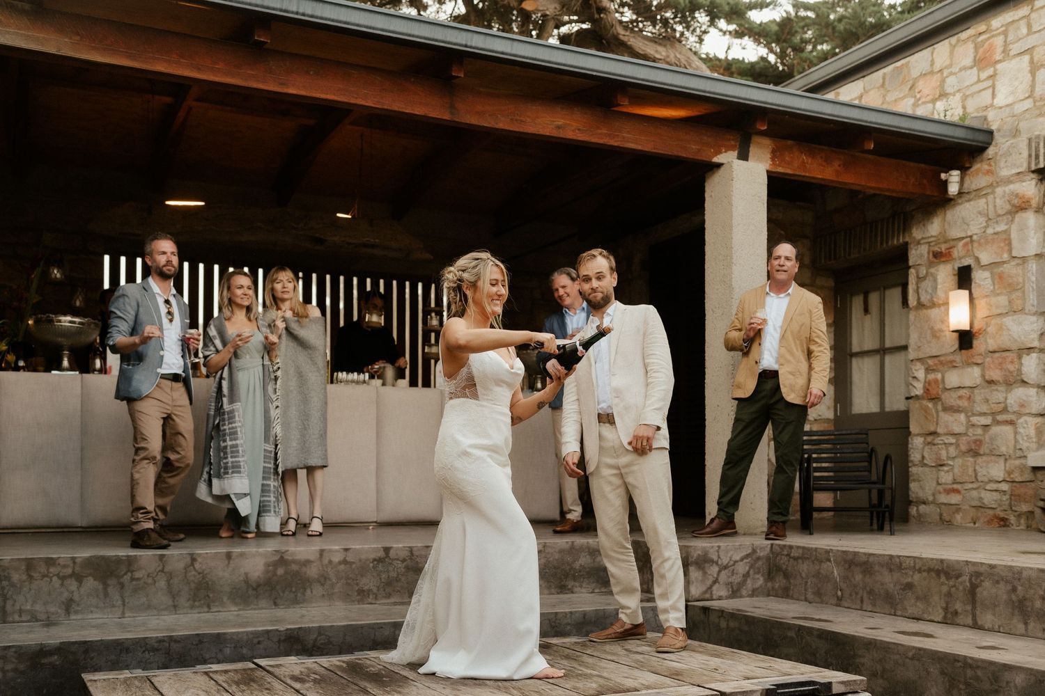 Outdoor wedding reception at stone venue with couple dancing on patio at dusk.