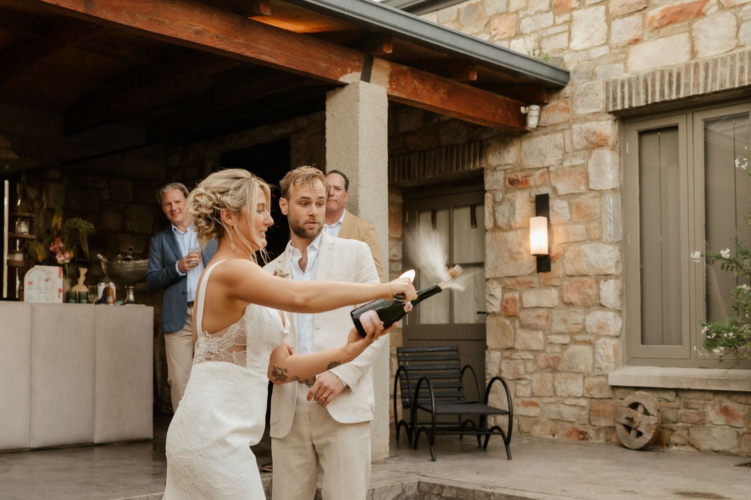 Newlyweds share their first dance on a stone patio during their wedding reception.