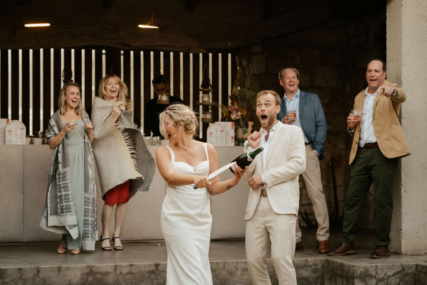 Wedding guests cheer and celebrate during a festive reception moment.