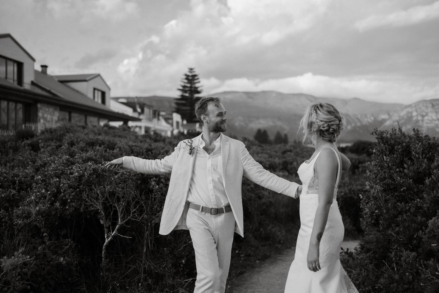Black and white portrait of a wedding couple sharing a joyful moment in a mountain setting.