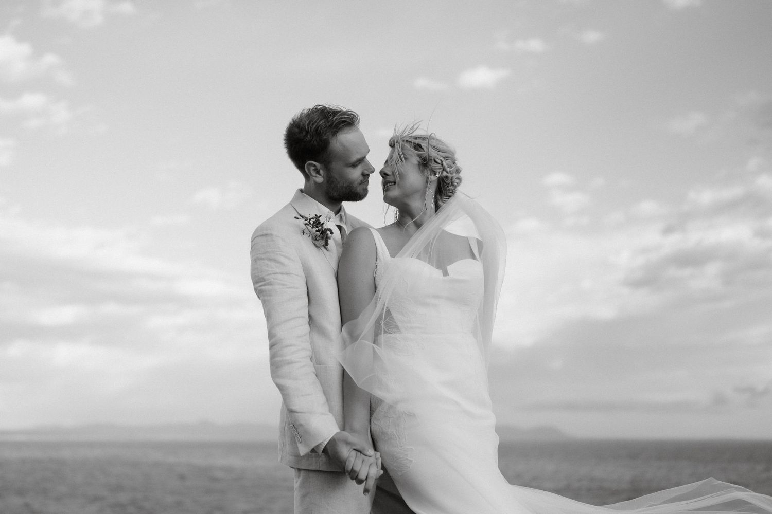 A black and white wedding portrait captured against an open sky and horizon.