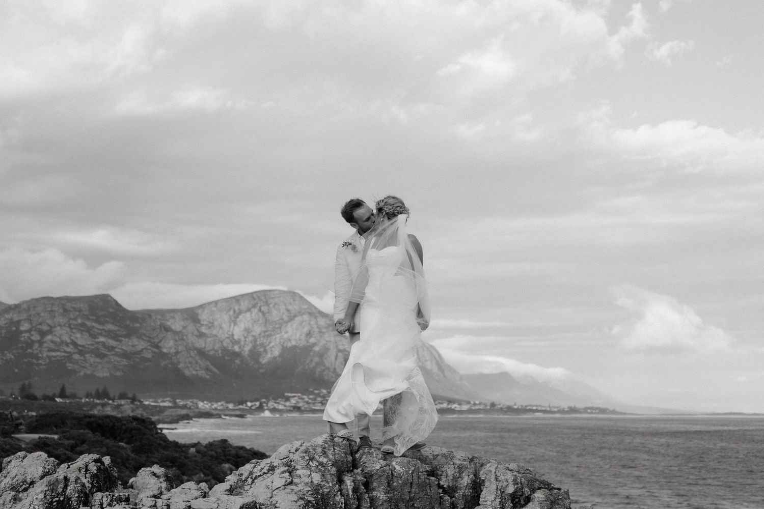 Black and white wedding portrait with dramatic mountain landscape in the background.