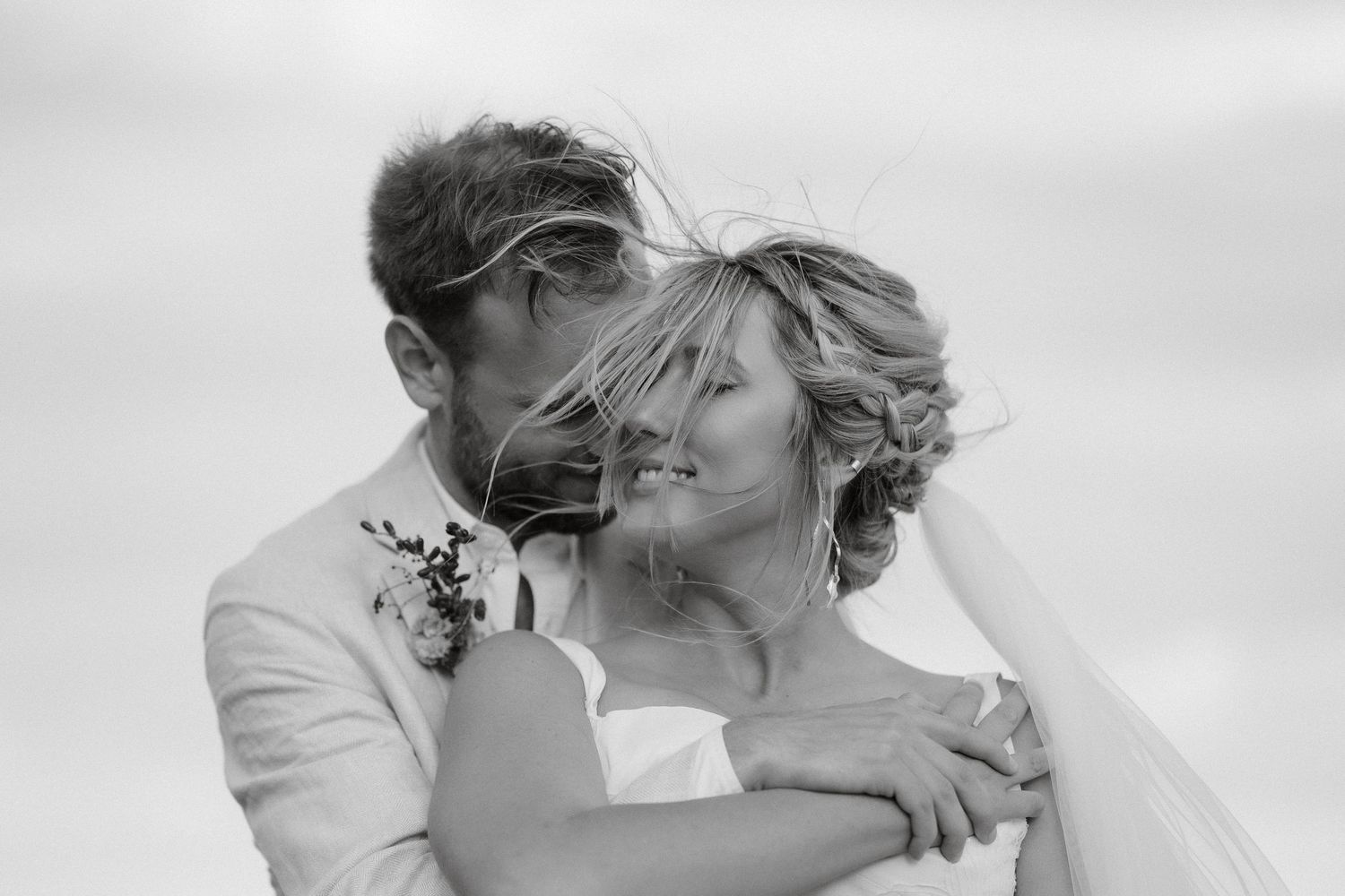 Intimate black and white portrait of newlyweds sharing tender moment outdoors.