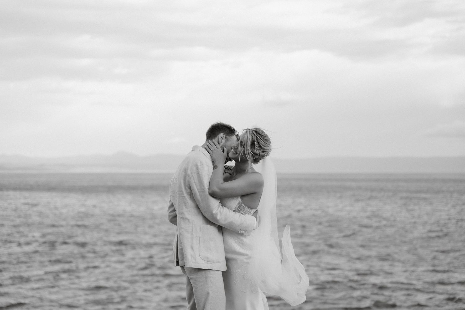 Intimate black and white moment of newlyweds by the ocean.