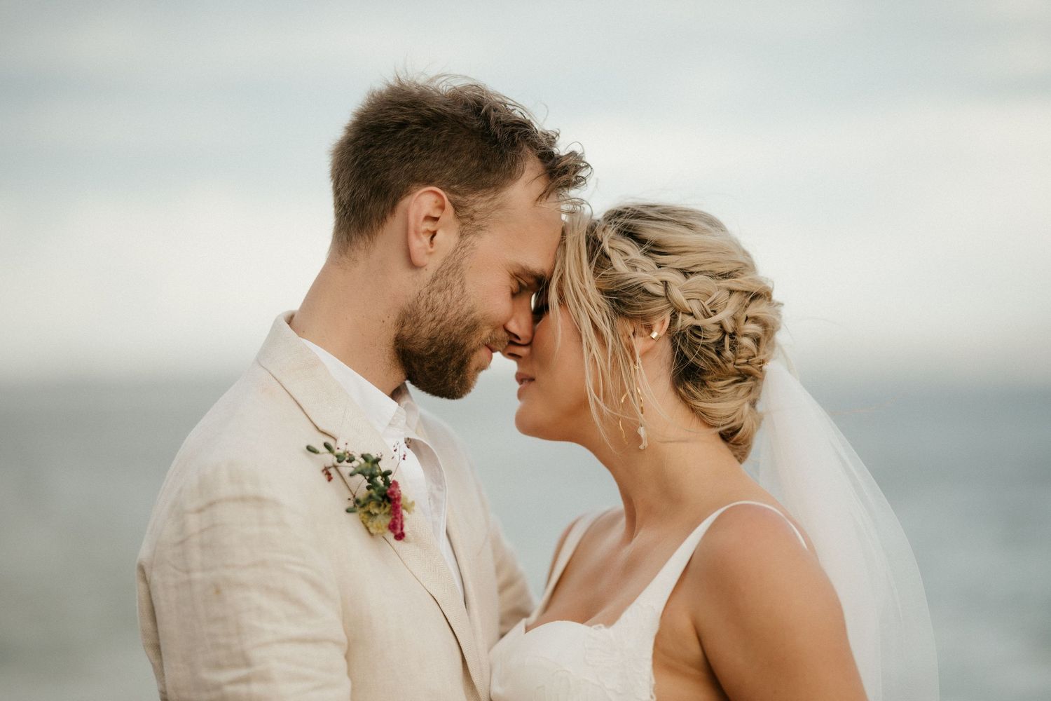 A tender moment shared between newlyweds against a misty ocean backdrop.