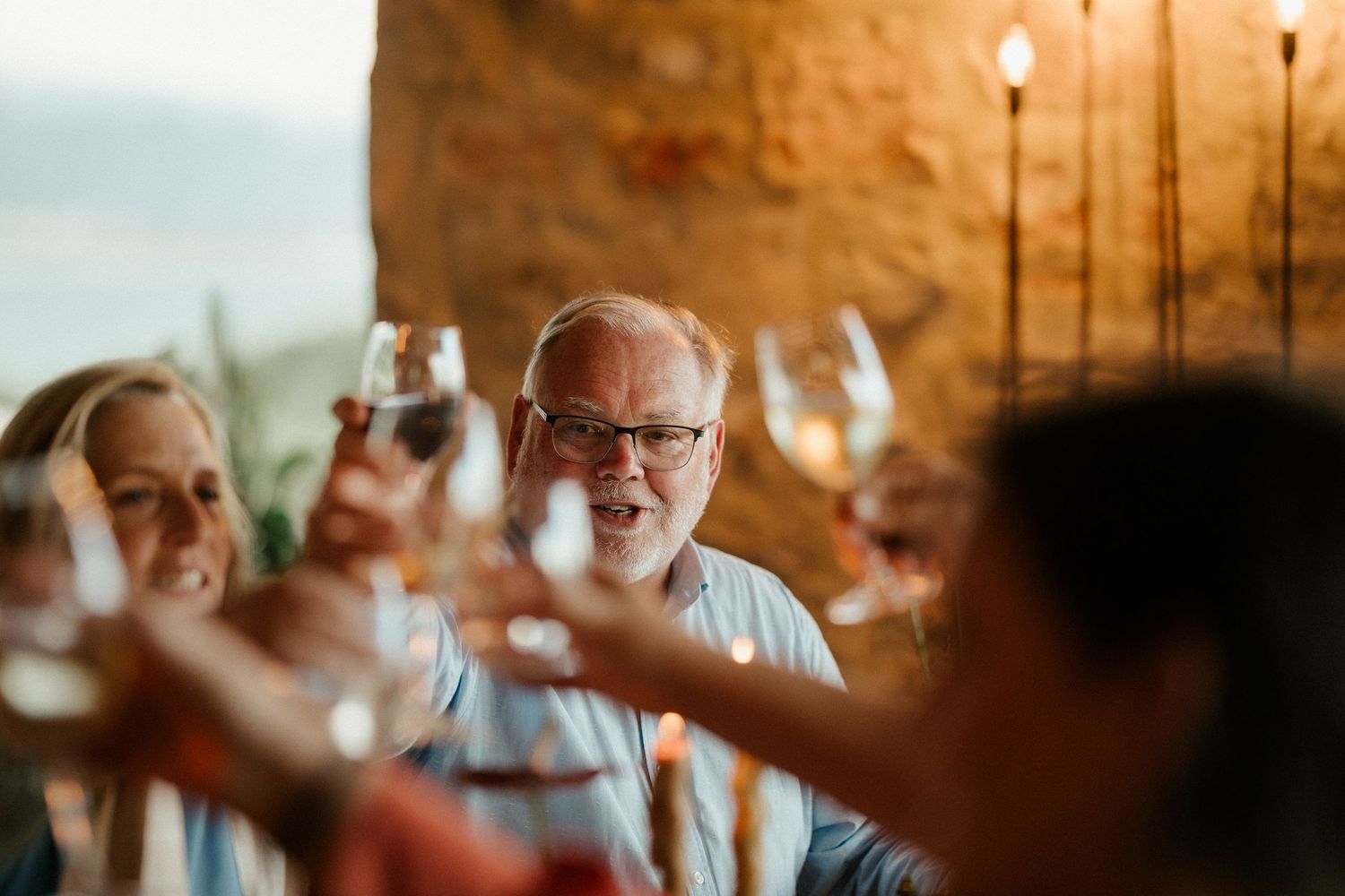Wedding guests raise their glasses in a celebratory toast during an indoor reception.
